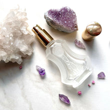 Cargar imagen en el visor de la galería, A crystal perfume bottle with a flower etched on the outside and gold sprayer top featuring a visible sprayer nozzle.