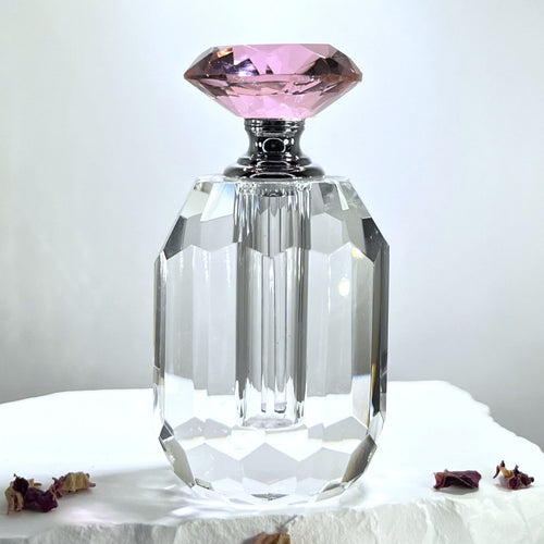 A Crystal Glass Perfume Bottle with an oval shape faceted cut crystal pink top. An empty perfume bottle.