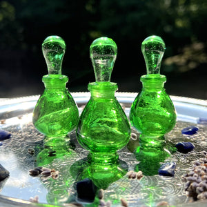 Green Glass Potion Genie Bottles on a silver tray sparkling in the sunshing. Imagine colorful perfume oils inside. GORGEOUS!