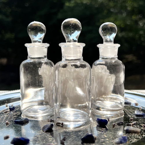 Clear Glass Apothecary Bottles in half ounce size on a silver tray sparkling in the sun. Reagent Bottles.