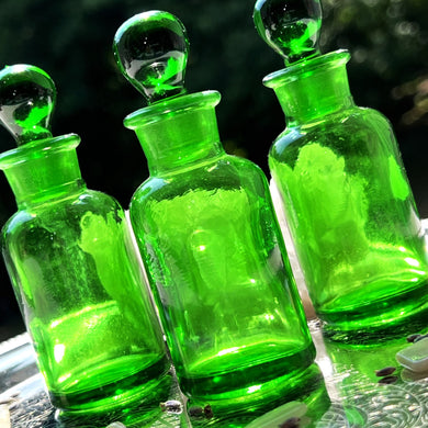 GREEN Glass Apothecary Bottles in one ounce size on a silver tray sparkling in the sunshine.