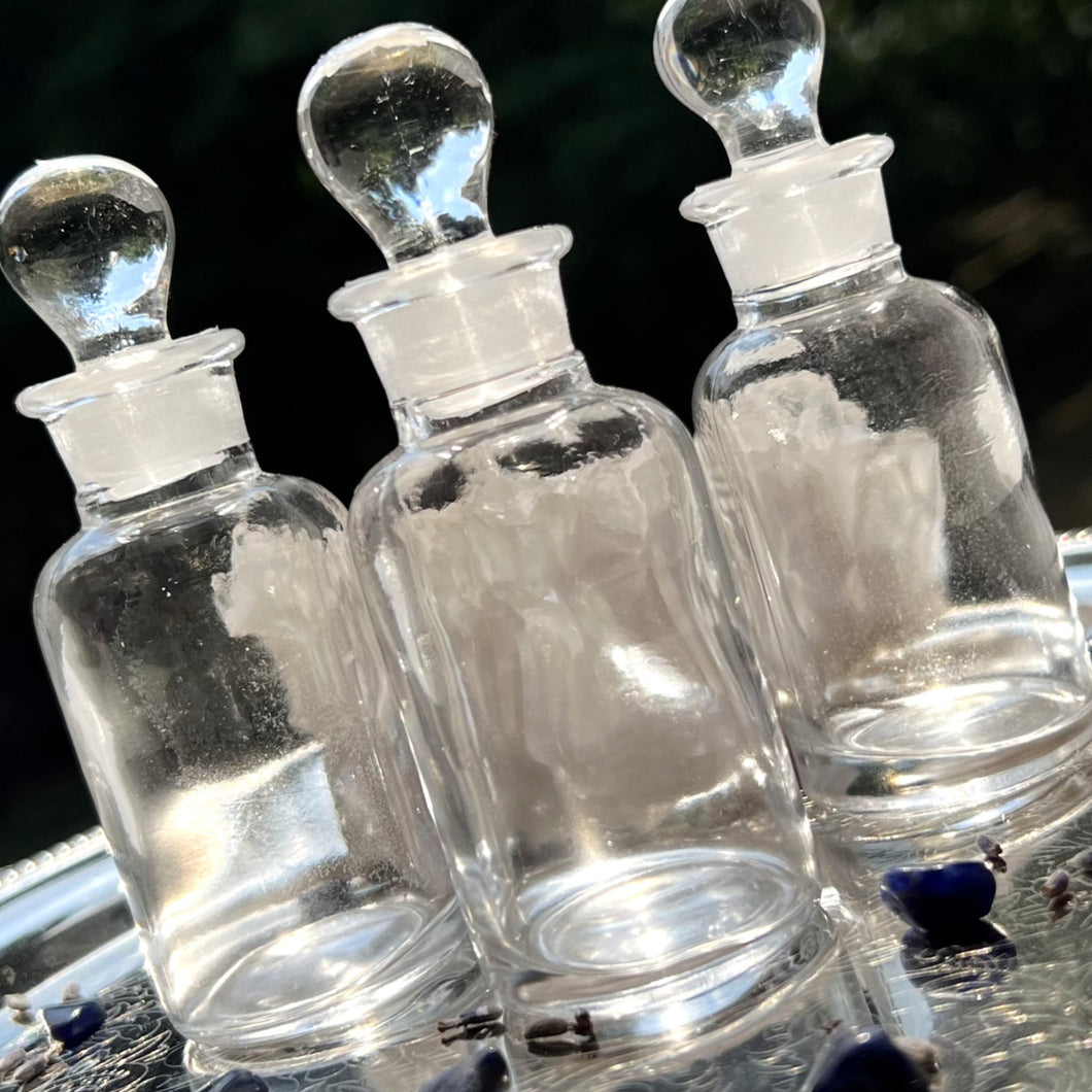 CLEAR Glass Apothecary Bottles in one ounce size on a silver tray sparkling in the sunshine.