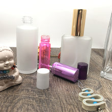 Load image into Gallery viewer, Assorted Perfume Bottles. Our focus is the 2 oz. Perfume Spray bottles. Frosted Glass with Purple Atomizer Sprayer Top and Over Cap for Perfume Oils, Essential Oils or Fragrance Oils.