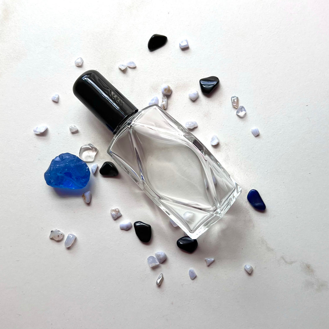 Fragrance oil glass bottle with a black cap surrounded by crystals you can place inside for your private label line!