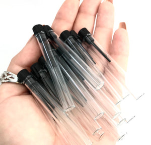 Many 1.5 ml clear glass soda-lime vials in a human hand to show size comparison. Great for carrying small pills or glitter!